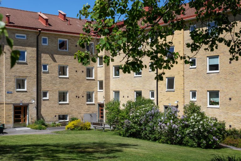 Ett flerbostadshus med gräsmatta och träd.