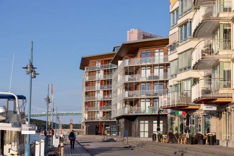 En man går längs en gata bredvid höga byggnader.