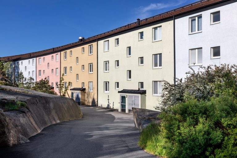 En rad flerfärgade hyreshus på en solig dag.