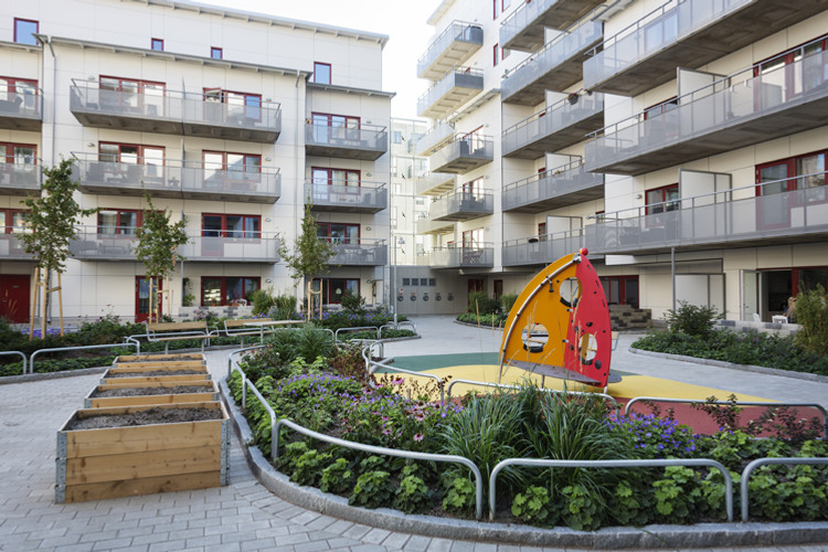 En innergård med lekplats och flera balkonger.