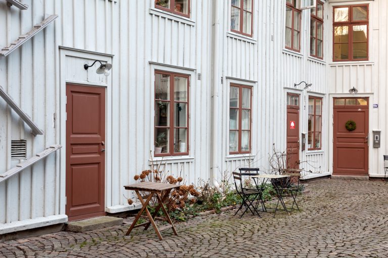 En rad vita byggnader med röda dörrar och fönster.