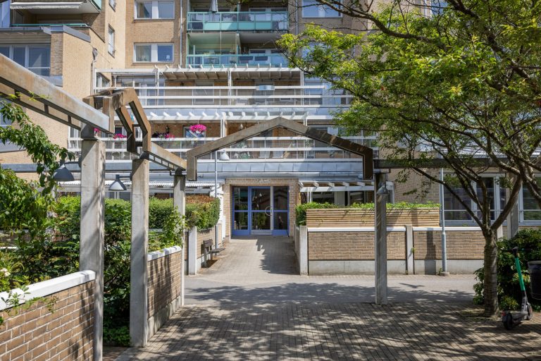 En byggnad som har många träd framför sig.