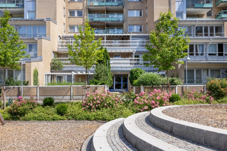 En stor byggnad med många balkonger intill en trädgård.