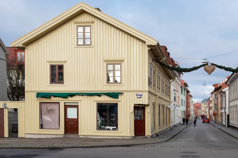 En smal gata med en gul byggnad och en grön markis.