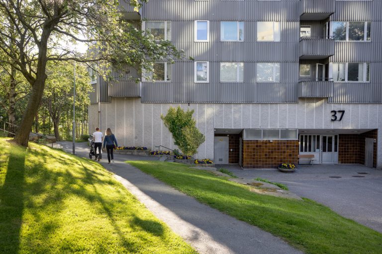 Några personer som går på en trottoar bredvid en hög byggnad.