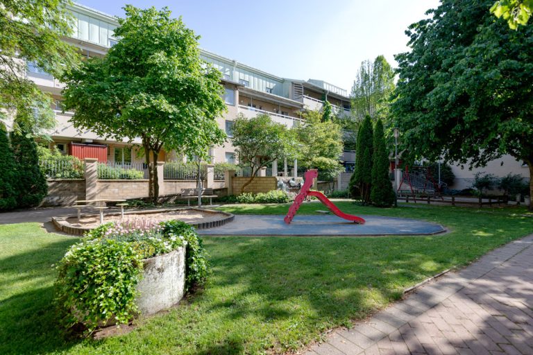 En innergård med en lekplats mitt i den.