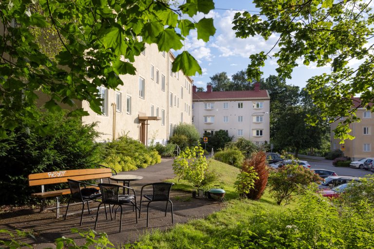 Ett bord och stolar i en trädgård intill en byggnad.