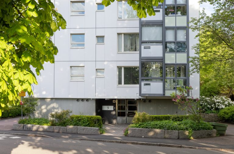 En hög vit byggnad som ligger vid sidan av en väg.