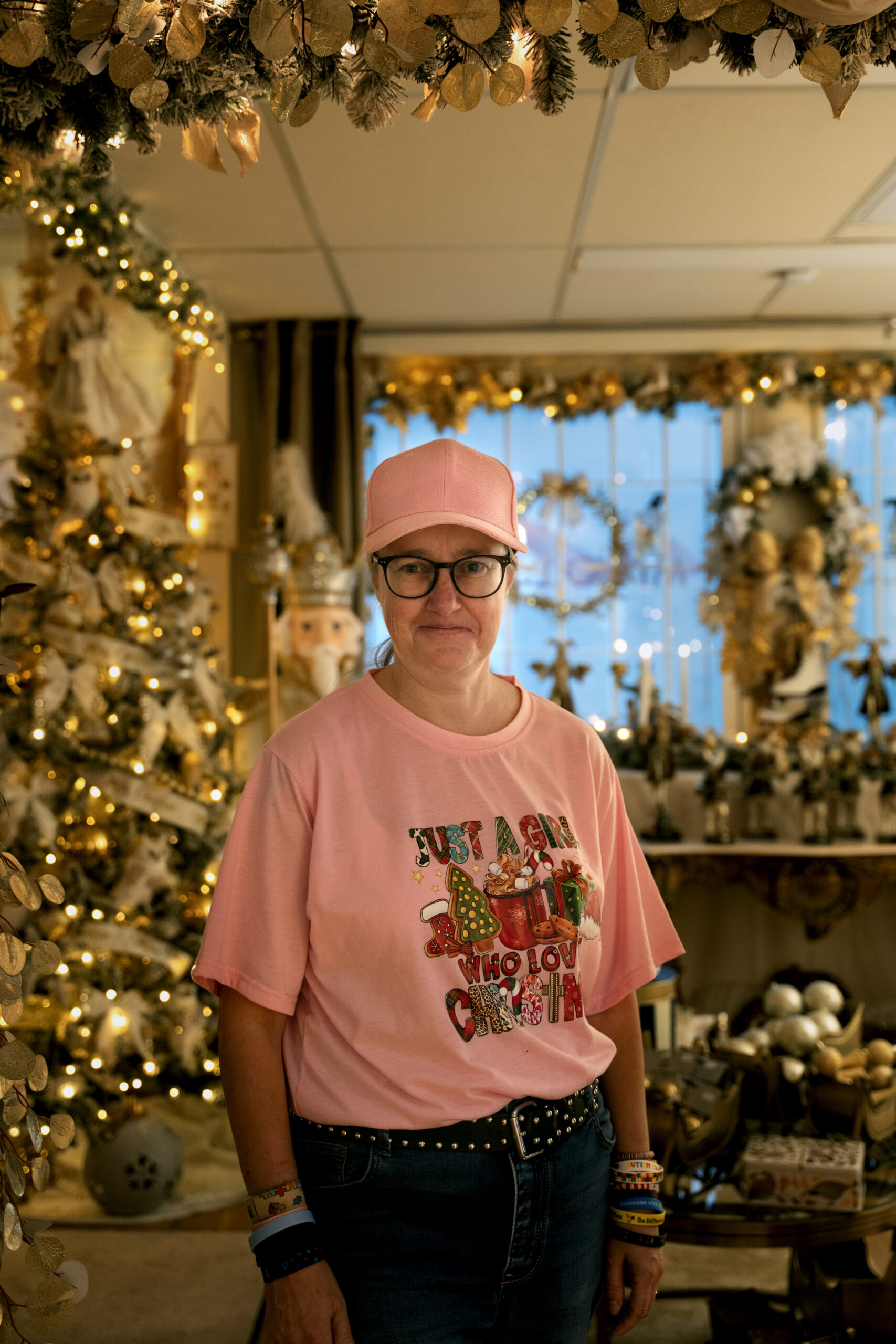 En leende kvinna står framför en julgran och en massa julpynt.