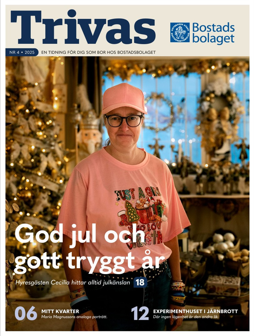 Kvinna i rosa tröja och glasögon ler in i kameran. Bakom henne syns en julgran och juldekorationer. Text i bild: "Trivas: God jul och gott tryggt år"