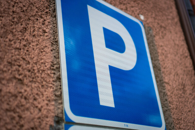 Blå parkeringsskylt framför en röd tegelvägg.