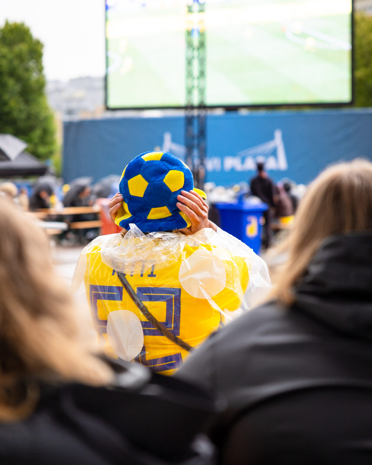 Fotbollssupporter med gul-blåa Sverigekläder och hatt på huvudet.