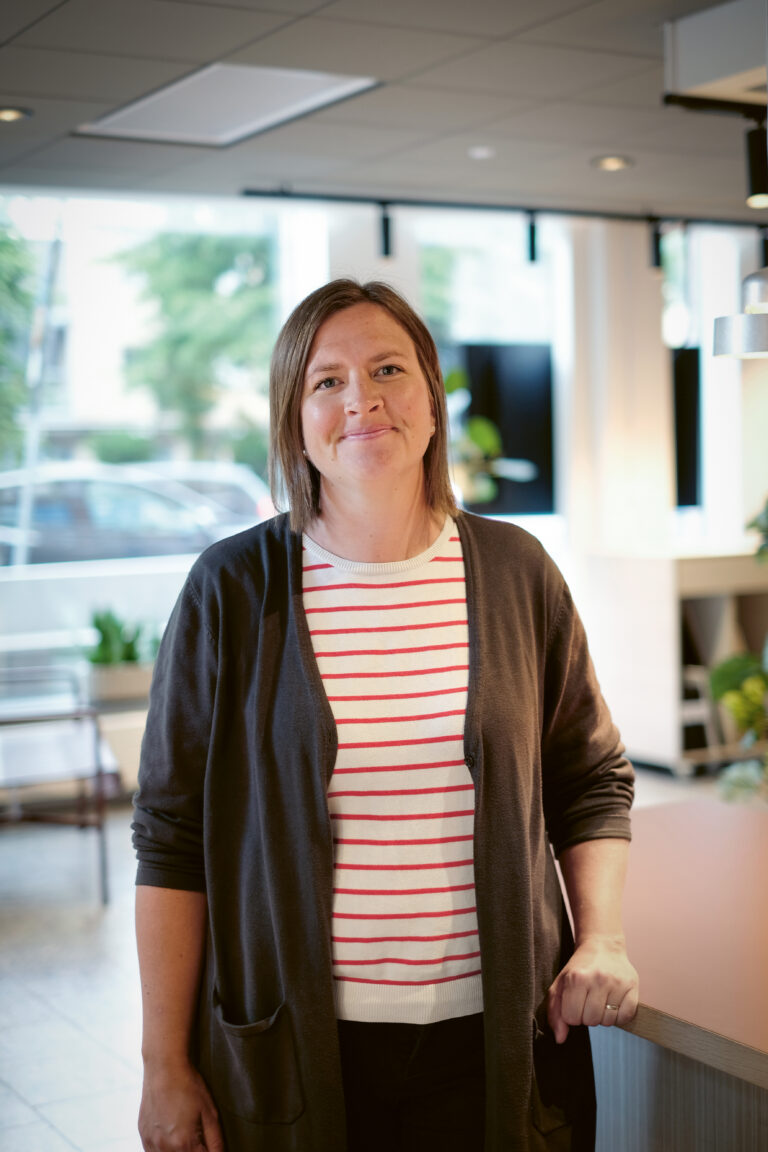 En kvinna som står på ett kontor med händerna i fickorna.