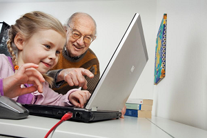 Flicka och morfar tittar på en dator tillsammans