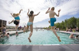 Tre barn hoppar i en pool.