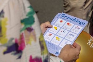 En hand håller en bingobricka som det står Grannbingo på.