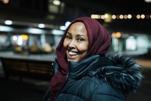 En kvinna i vinterkläder ler in i kameran.