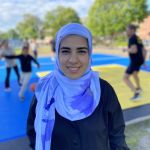 Initiativtagaren Shalla står leende framför basketplanen iklädd en ljusblå slöja och svart tröja.