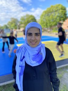 Initiativtagaren Shalla står leende framför basketplanen iklädd en ljusblå slöja och svart tröja.