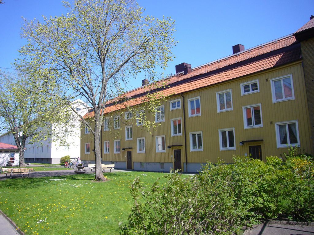 Bilden visar ett gulmålat tvåvåningshus som Bostadsbolaget äger i Rambergsstaden, Göteborg