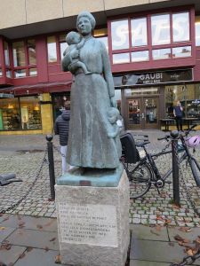 Skulptur som föreställer en kvinna med ett barn i famnen och ett i handen.