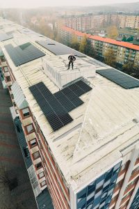 Flygfoto som föreställer en man på ett höghustak med solpaneler.