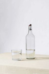 En flaska med vatten och ett tomt glas bredvid.