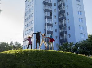 Barn hoppar på en kulle framför ett hus