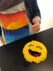 En smile-figur av garn visas upp tillsammans med en t-shirt med eget tryck.