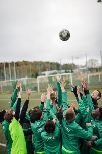 En grupp pojkar i fotbollskläder sträcker sig efter en boll i luften.