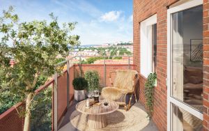 Illustrationsbild av balkong, med utsikt över takåsar. På balkongen finns en fåtölj och litet bord samt gröna växter.